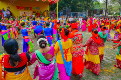 Blurred image of Kolkata India. Girl dancers dressed in colourful sari  traditional Indian dress  and Palash flowers  Butea monosperma  make up dancing at Dol  in Bengali  or Holi  in Hindi  festival.