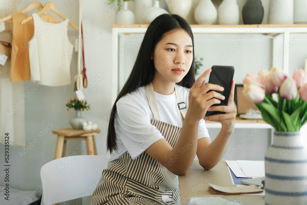 Young asian business owner holding phone and retail package parcel. Young asian business owner holding phone and retail package parcel.