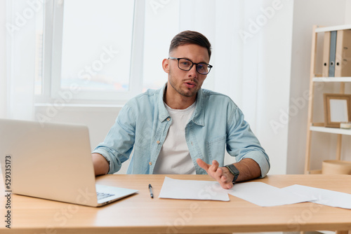 Serious friendly handsome stylish young businessman in eyewear talks with candidate at vacancy looks at camera reclines on table. Copy space for ad. Remote Job Technology And Career Profession Concept