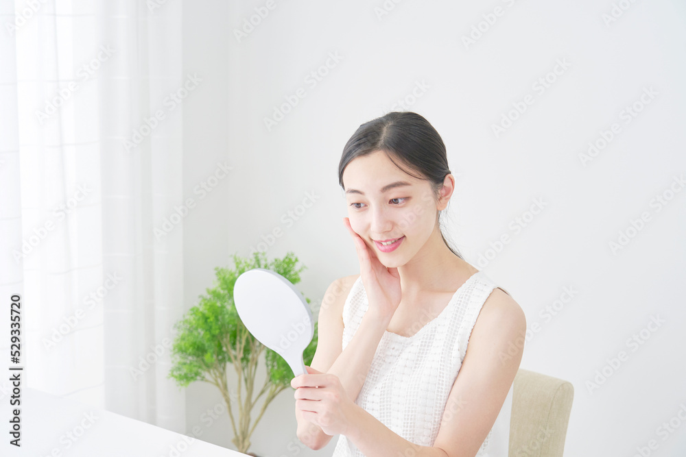 リビングでハンドミラーで顔を見る女性