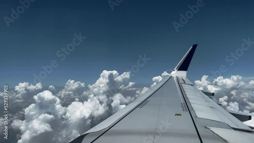 Airplane Passengers seat point of view plane wings cross blue sky over scenic formation cumulus clouds. Copy space flight and sky background photo