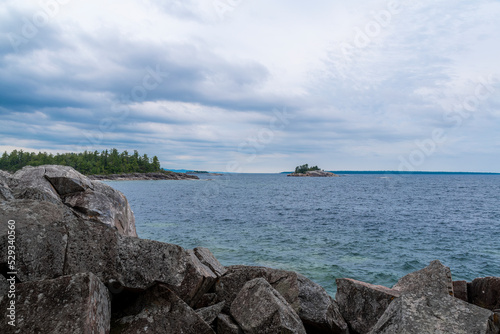 Lake Superior hides behind a large pile of rocks with an island seen in the distance, from the Agawa Bay Pictographs trail. photo