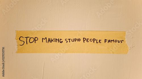 Fotografia word text of stop making stupid people famous written on duct tape isolated on dirty white wall
