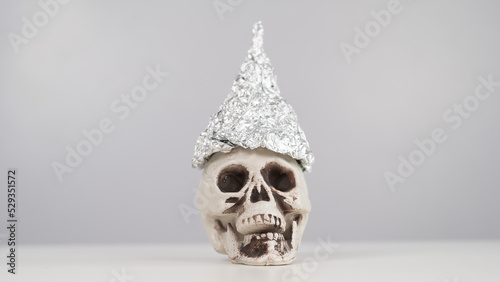 Plastic skull in a tinfoil cap on a white background. Copy space. 
