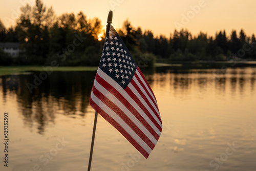 Fototapeta Naklejka Na Ścianę i Meble -  American flag on the sunset lake background. USA holiday concept