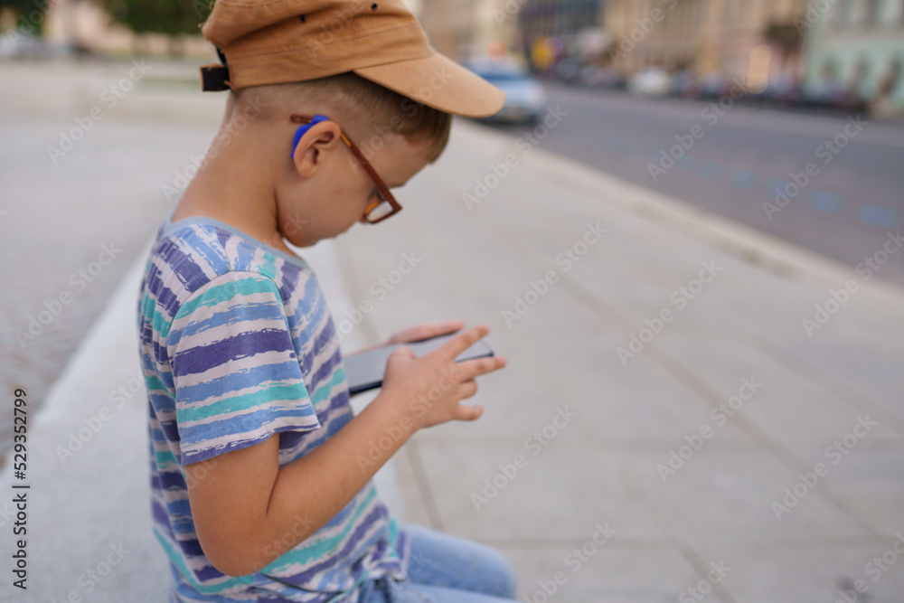 6 year old boy using smart phone outdoors 