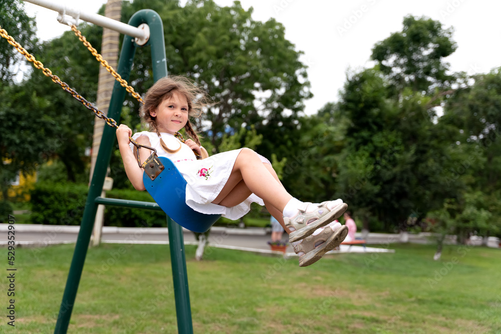 Happy beautiful little girl having fun on a swing. Girl riding on a swing Happy beautiful little girl having fun on a swing. Girl riding on a swing