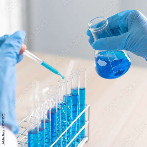 Murais de parede Scientists are carrying blue chemical test tubes to prepare for the determination of chemical composition and biological mass in a scientific laboratory, Scientists and research in the lab Concept