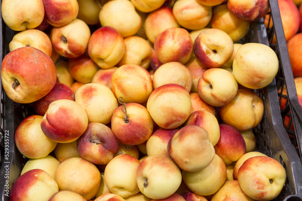 Juicy ripe nectarines in a box in a store. Fruit and vegetable department in the supermarket. Vitamins and healthy food. Close-up. Juicy ripe nectarines in a box in a store. Fruit and vegetable department in the supermarket. Vitamins and healthy food. Close-up.