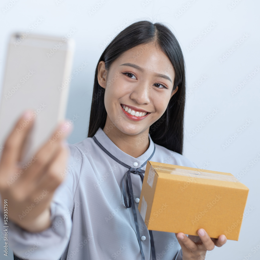 Business women selling online are taking pictures of themselves and their merchandise as a confirmation of delivery to customers, Selling products online or doing freelance work at home concept. Business women selling online are taking pictures of themselves and their merchandise as a confirmation of delivery to customers, Selling products online or doing freelance work at home concept.