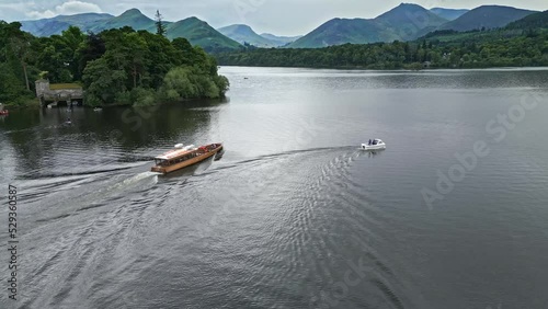 Drone Aerial footage of a river boat on Derwentwater, Keswick, a calm lake with river boats and a stormy sky. Surrounded by mountain's, hills and lush woodland. photo