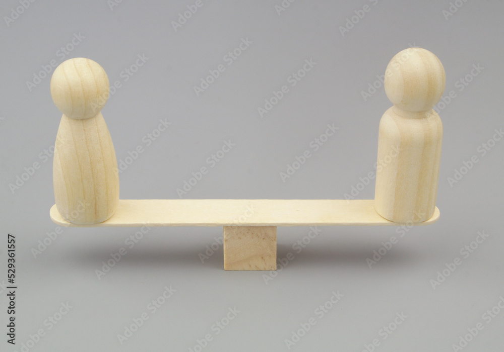 Gender equality concept. Male and female wooden figures on balance scales. Gender equality concept. Male and female wooden figures on balance scales.