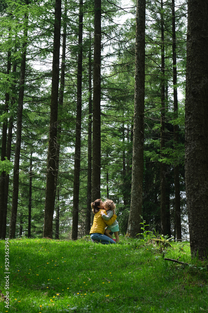 little happy girl hugging her beautiful and mother in the forest. Mother's Love little happy girl hugging her beautiful and mother in the forest. Mother's Love