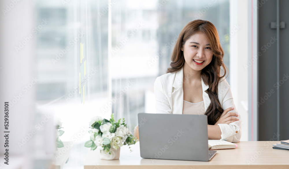 Beautiful businesswoman sitting at desk and look at the camera at the office. Beautiful businesswoman sitting at desk and look at the camera at the office.