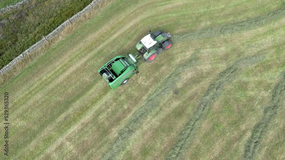 Aerial video of Hay bale tractor. Tractor harvesting hay into bales in field near Halifax, England, on a hot and sunny day. Aerial video of Hay bale tractor. Tractor harvesting hay into bales in field near Halifax, England, on a hot and sunny day.