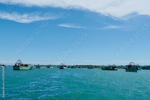 Fishing boats floating on the calm blue sea water in the Pamban island in Rameshwaram, Tamilnadu, India. Monsoon season fishing in India. Fishing boats in the harbor. © Prabhakarans12