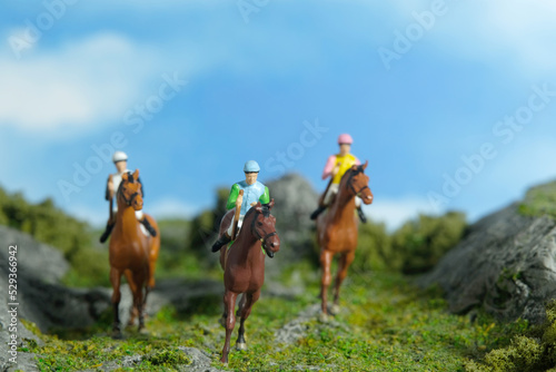 Miniature people toy figure photography. A jockey man riding horse at mountain hill for training