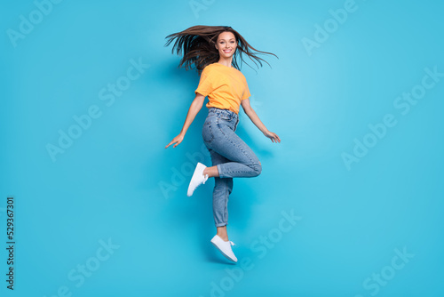 Fototapeta Naklejka Na Ścianę i Meble -  Full length photo of sweet shiny girl dressed yellow t-shirt smiling jumping high isolated blue color background
