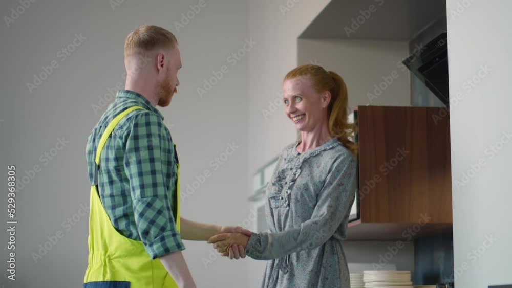 Professional repairman in overalls check household dishwasher in kitchen after installing. Realtime