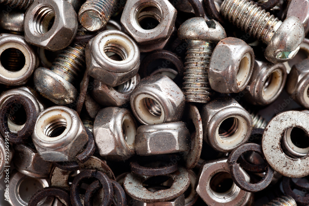 Bolts, nuts and washers, hardware lying in a round container.