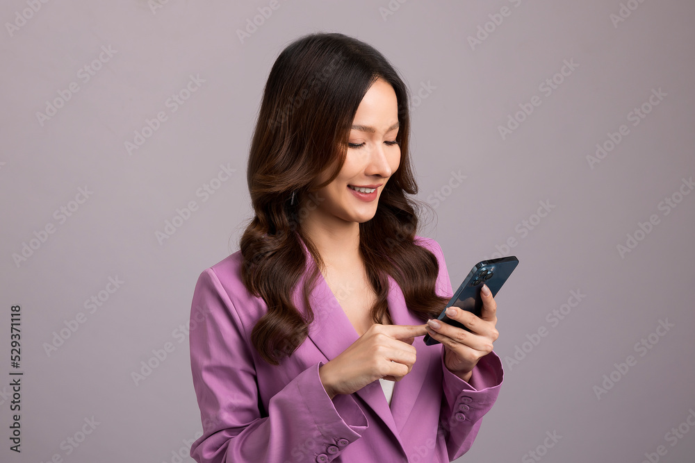 Beautiful Asian womaa using smartphone standing isolated on gray background. Shopping online mobile phone. Beautiful Asian womaa using smartphone standing isolated on gray background. Shopping online mobile phone.