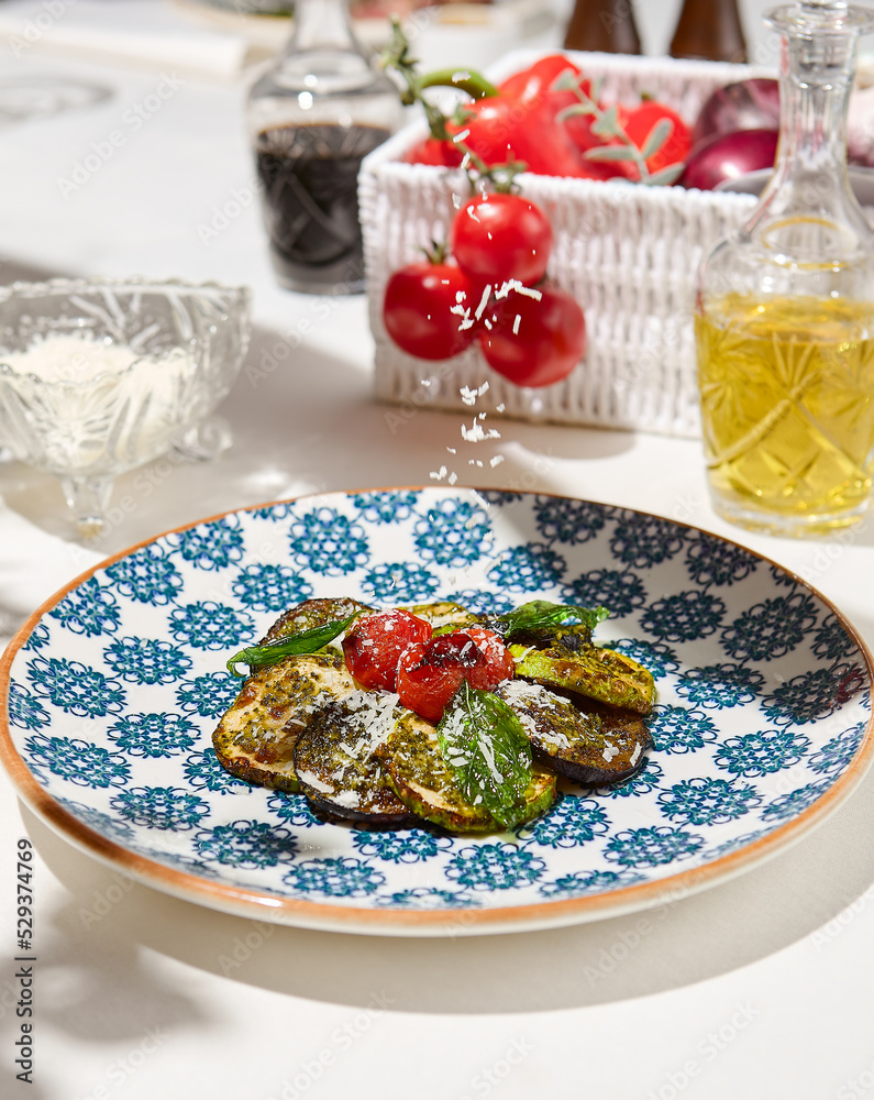 Grilled vegetables on light background with shadows. Salad with grilled zucchini, eggplant and tomatoes. Aesthetic composition with bbq vegetables. Vegan food. Grilled vegetables in Summer menu.