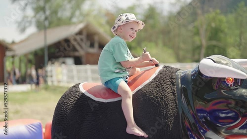 Kid on mechanical bull rodeo riding at western festival 4K photo