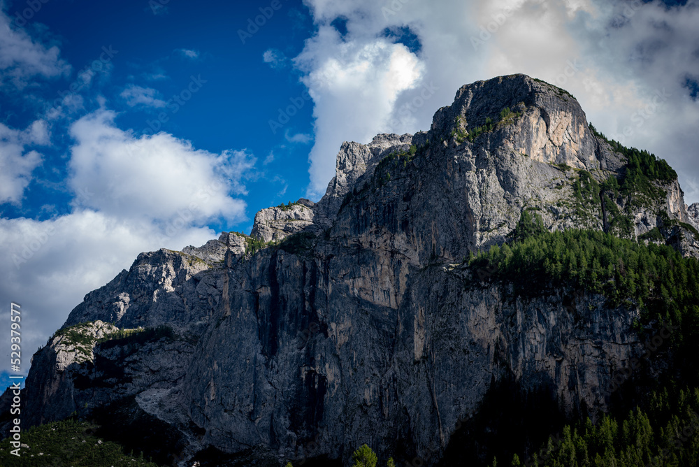 clouds over the mountains dolomiti, with blue sky and green trees in italy