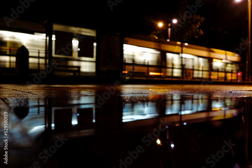 Public transport tram at night during rain storm reflected in puddle