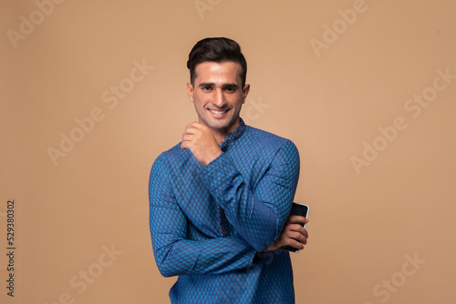 Young handsome Indian man wearing kurta with gifts in hand