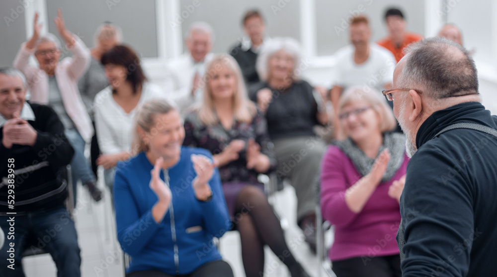 Mature caucasian man gives a speech in meeting in modern open office Mature caucasian man gives a speech in meeting in modern open office
