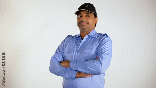 A middle-aged security guard standing with folded arms - unskilled labor  uneducated Indian man. A night watchman with stubble wearing in blue uniform - posing for the camera photo