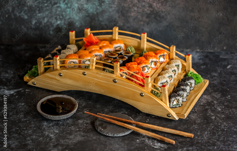 Sushi rolls Japanese delicacies. Japanese traditional rice and fish dishes. Beautiful serving food on a dark background with copy space. A set of delicious goodies. Sushi rolls Japanese delicacies. Japanese traditional rice and fish dishes. Beautiful serving food on a dark background with copy space. A set of delicious goodies.