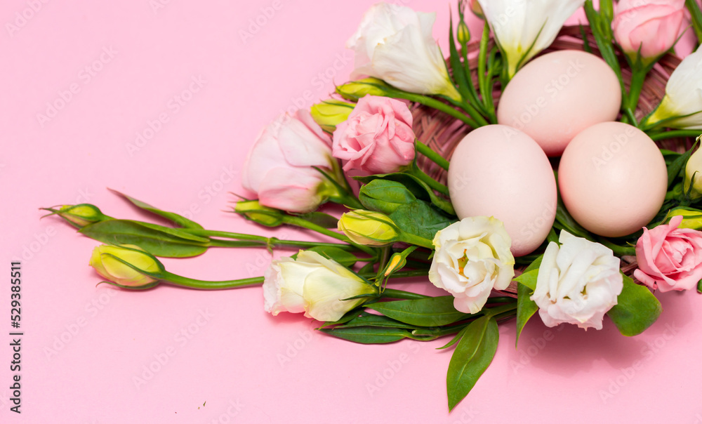 Obraz premium Easter background with Easter eggs and spring flowers. Top view with copy space. Nest with eggs decorated with beautiful flowers on a pink background.