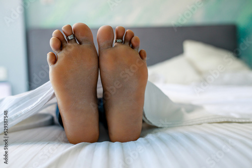 Close up of female feet in bed in bedroom under blanket photo