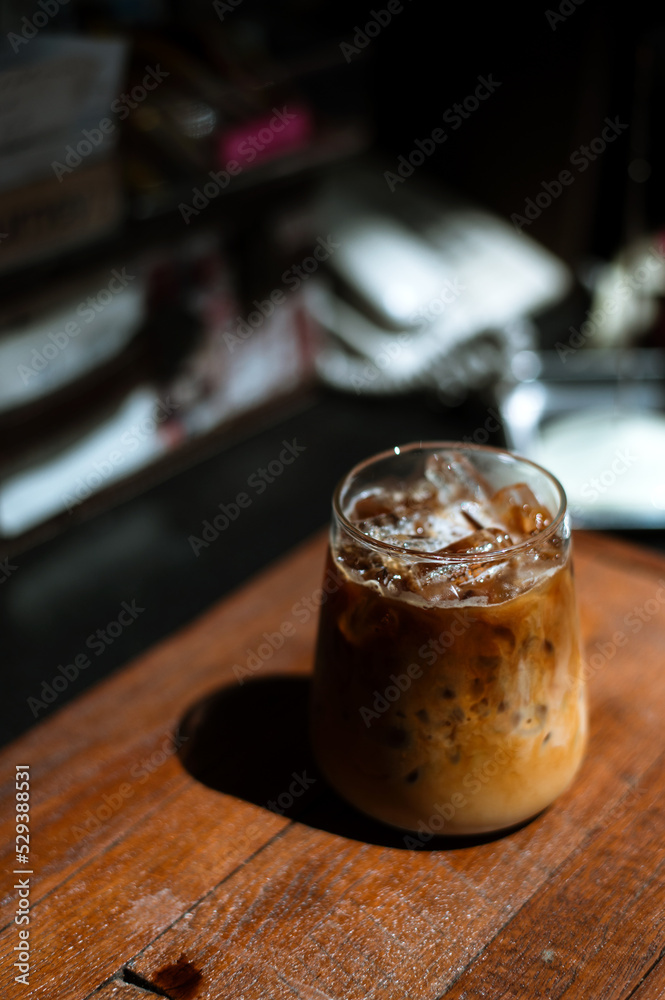 Ice coffee on a table with cream being poured into it showing the texture