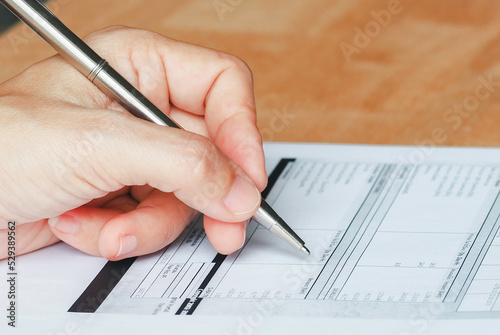 Businesswoman's hand with pen completing personal information on a form and office supplies on desk of working. Business Education concept. work at home