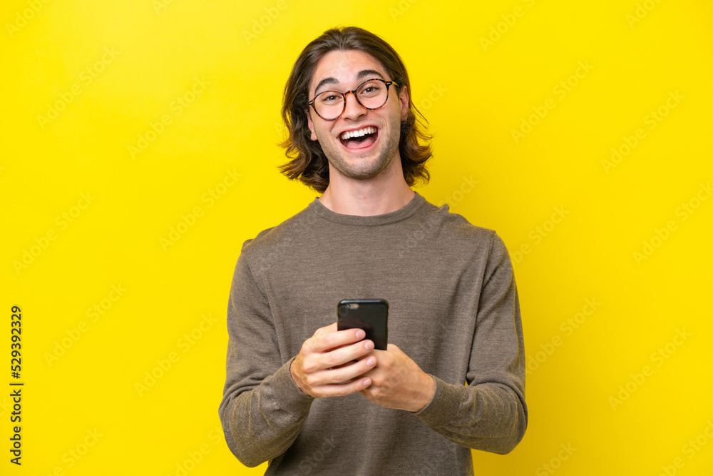 Caucasian handsome man isolated on yellow background surprised and sending a message Caucasian handsome man isolated on yellow background surprised and sending a message
