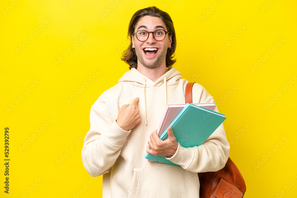 Young student handsome man isolated on yellow background with surprise facial expression Young student handsome man isolated on yellow background with surprise facial expression