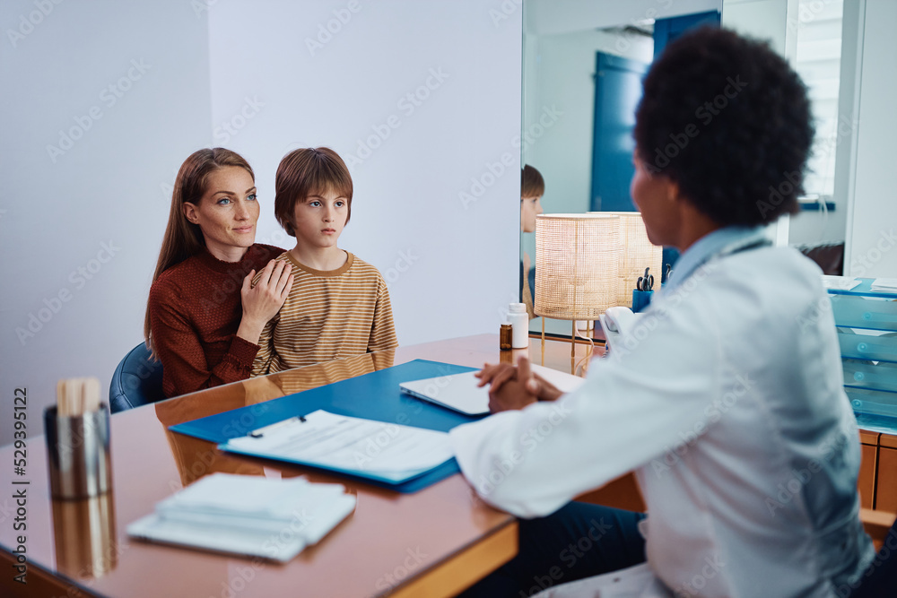 Smiling mother and son talk to black female pediatrician at doctor's office. Smiling mother and son talk to black female pediatrician at doctor's office.