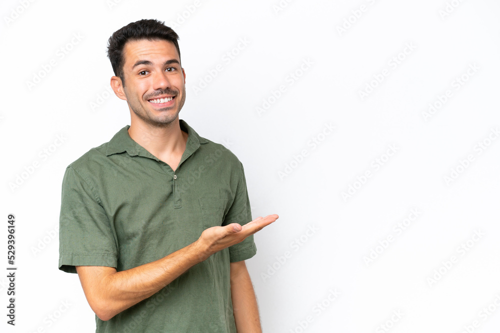 Young handsome man over isolated white background presenting an idea while looking smiling towards Young handsome man over isolated white background presenting an idea while looking smiling towards
