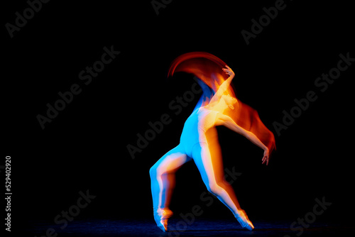 Ease of movement. Tender female ballet dancer dancing solo dance over dark background in mixed neon light. Art, flexibility, inspiration and beauty concept. © master1305