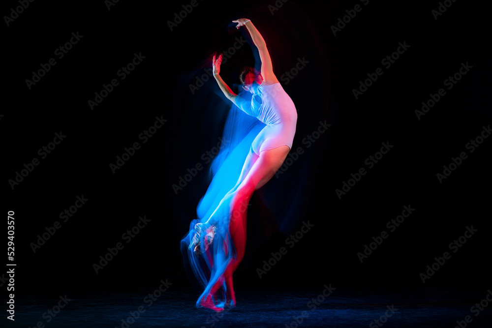 Flight. Tender female ballet dancer dancing solo dance over dark background in mixed neon light. Art, flexibility, inspiration and beauty concept.