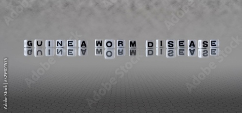 guinea worm disease word or concept represented by black and white letter cubes on a grey horizon background stretching to infinity