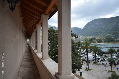 a long balcony with columns and arches and a view of the Bay of Kotor of the Adriatic Sea