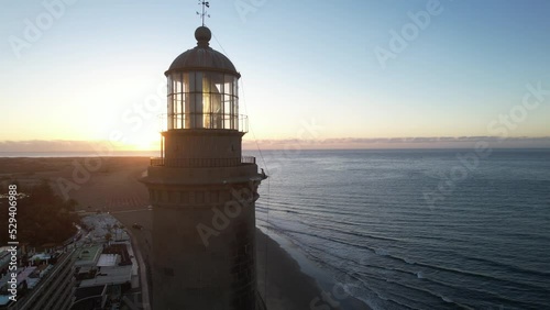 Fantastic aerial shot from a short distance from the top of the lit lighthouse and during the golden hour. Located on the beach of Maspalomas, Gran Canaria. photo