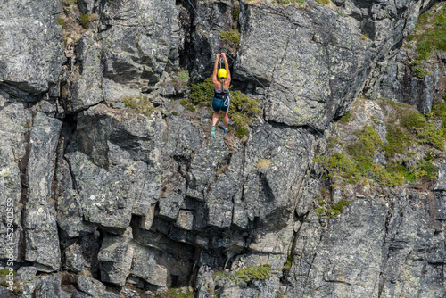 Woman from behind in flight hanging from a cable extreme sports in Norway.