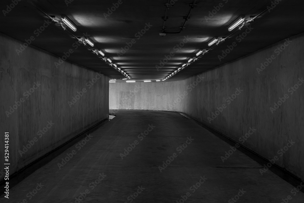 Road tunnel black and white, night illuminated, Urban tunnel without traffic, illuminated city highway tunnel with spotlights black and white.