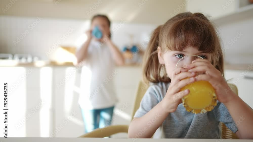 children drink juice. little girl in the kitchen drinking yellow juice from a glass cup. happy family kid dream concept. children drink juice in the kitchen. healthy eating lifestyle concept children drink juice. little girl in the kitchen drinking yellow juice from a glass cup. happy family kid dream concept. children drink juice in the kitchen. healthy eating lifestyle concept
