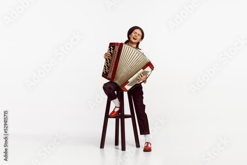 Portrait of talented beautiful woman playing accordion isolated over white studio background. Emotions